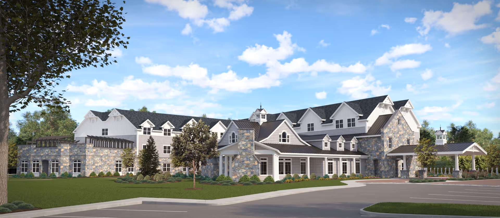 Front exterior of a large stone-and-siding senior living facility with landscaped grounds and a parking area under a blue sky.