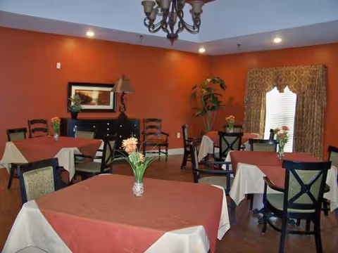 Dining room with red walls, burgundy and white tablecloths, and centerpieces.