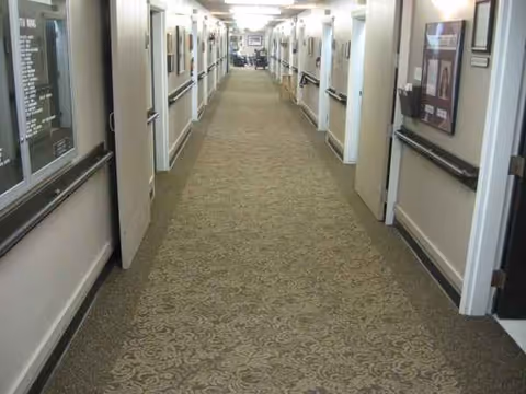 Long hallway in a senior living facility with framed pictures along the walls.