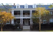 Two-story building with a white front porch and fall trees framing the Lydia H. Roper Home.
