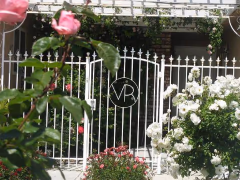 White wrought iron gate with a circular VR emblem framed by roses.