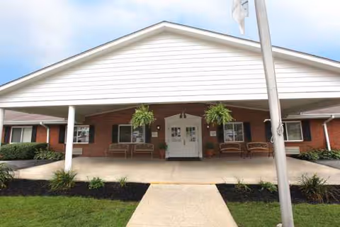 Front entrance of The Laurels of Hillsboro senior living with brick exterior and benches.