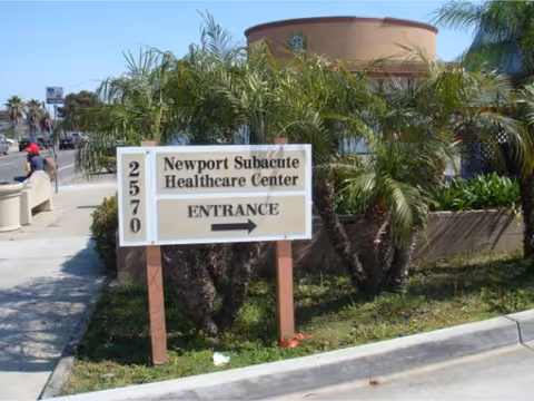 A sign reading Newport Subacute Healthcare Center Entrance sits beside palm trees.