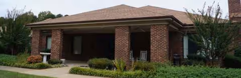 A brick senior living facility front with a covered entrance and well-kept landscaping.