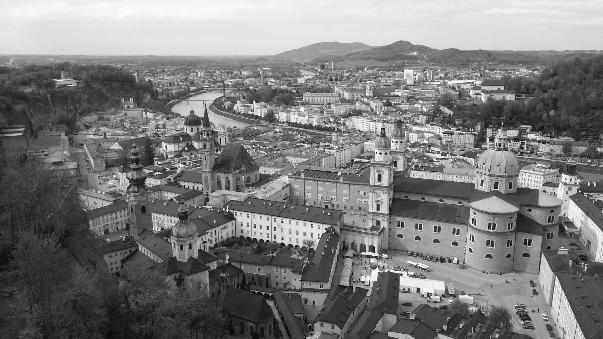 Aerial black-and-white view of a European town with domed churches and dense rooftops.