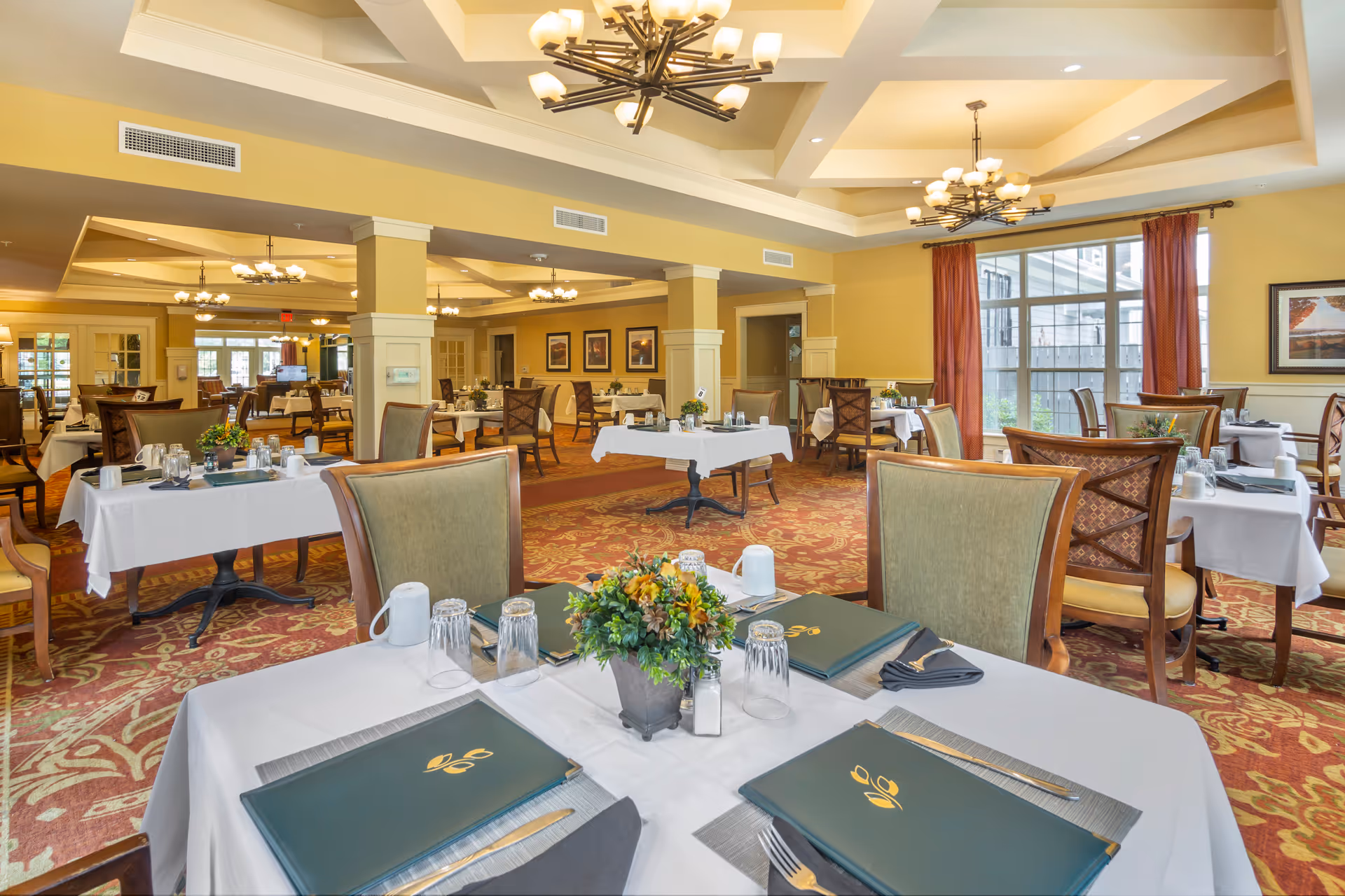 Bright, elegant dining room with tables set with menus, place settings, and floral centerpieces.