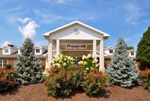 Exterior view of Five Star Residences of Northwoods entrance with landscaped shrubs and a welcome sign