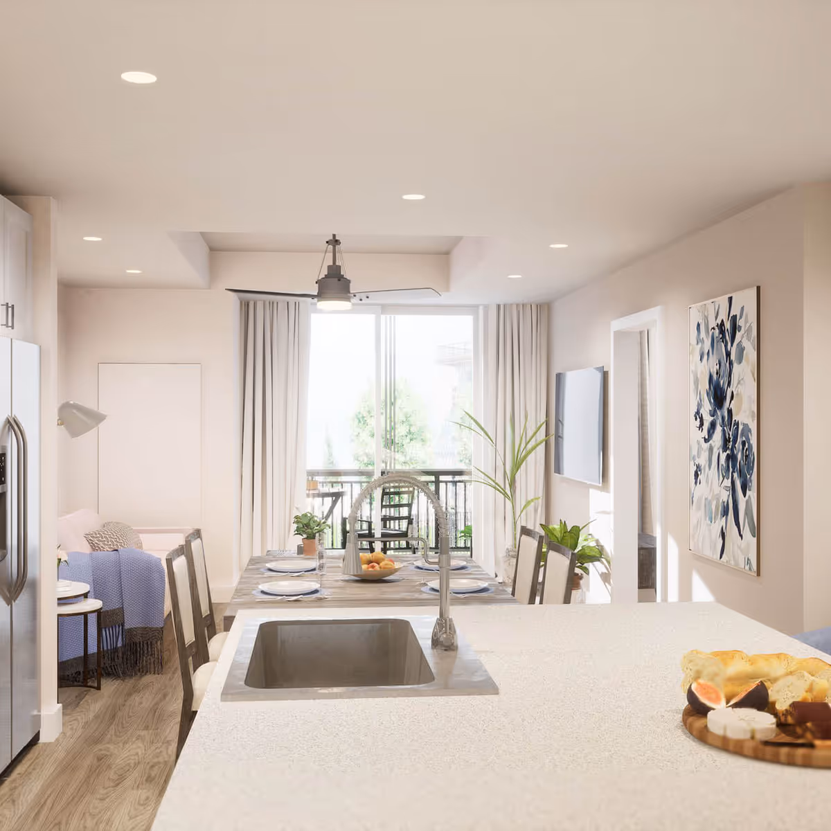 Bright and modern open-concept living space featuring a kitchen island with a sink and a plate of bread and cheese, a dining table set with plates and glasses, a living area with a sofa and a floor lamp, a wall-mounted TV, large windows with curtains, and a balcony with outdoor chairs.