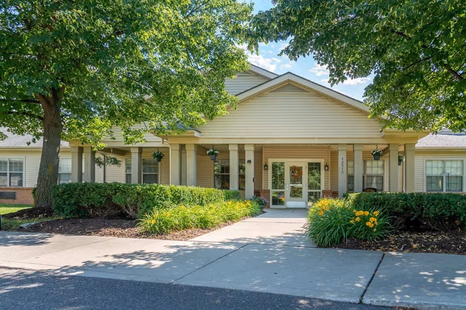 Front view of Addington Place of Northville entrance with columns and landscaping