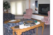 A living room at Willows senior facility with sofas, a coffee table, and a fireplace.
