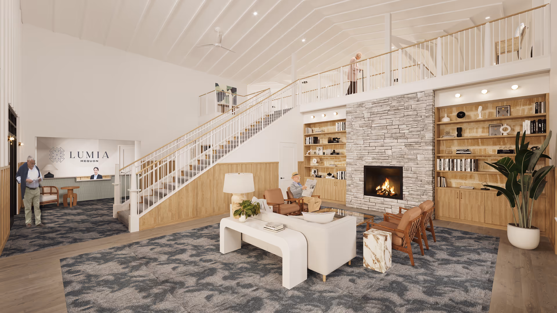 A spacious and well-lit assisted living facility common area with a modern stone fireplace surrounded by built-in wooden bookshelves. The room features comfortable seating including a white sofa, brown leather chairs, and a small marble side table. A large patterned carpet covers the floor. A staircase with white railings leads to an upper level where a person is walking. Another person is seated near the fireplace reading a newspaper. In the background, a reception desk with a staff member is visible under a sign that reads 'Lumia Mequon'.