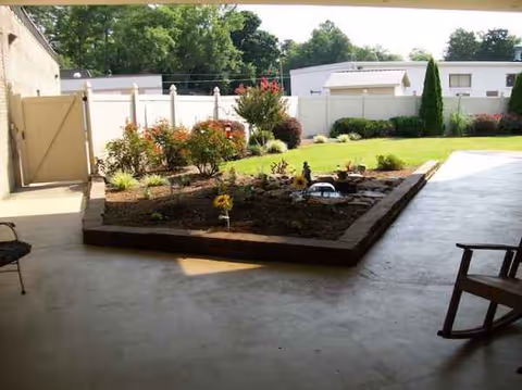 View of a covered patio with a raised garden bed and lawn beyond.