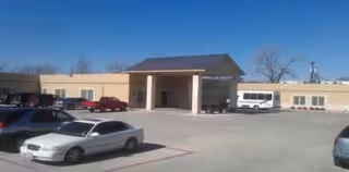 Exterior view of Garland Nursing & Rehabilitation Center with a covered entrance and parked cars.