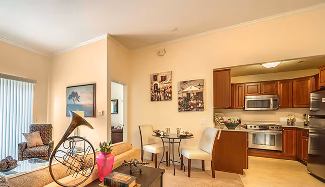 Open-concept living room and kitchen with a sofa, chairs, small dining table, and wood cabinets.