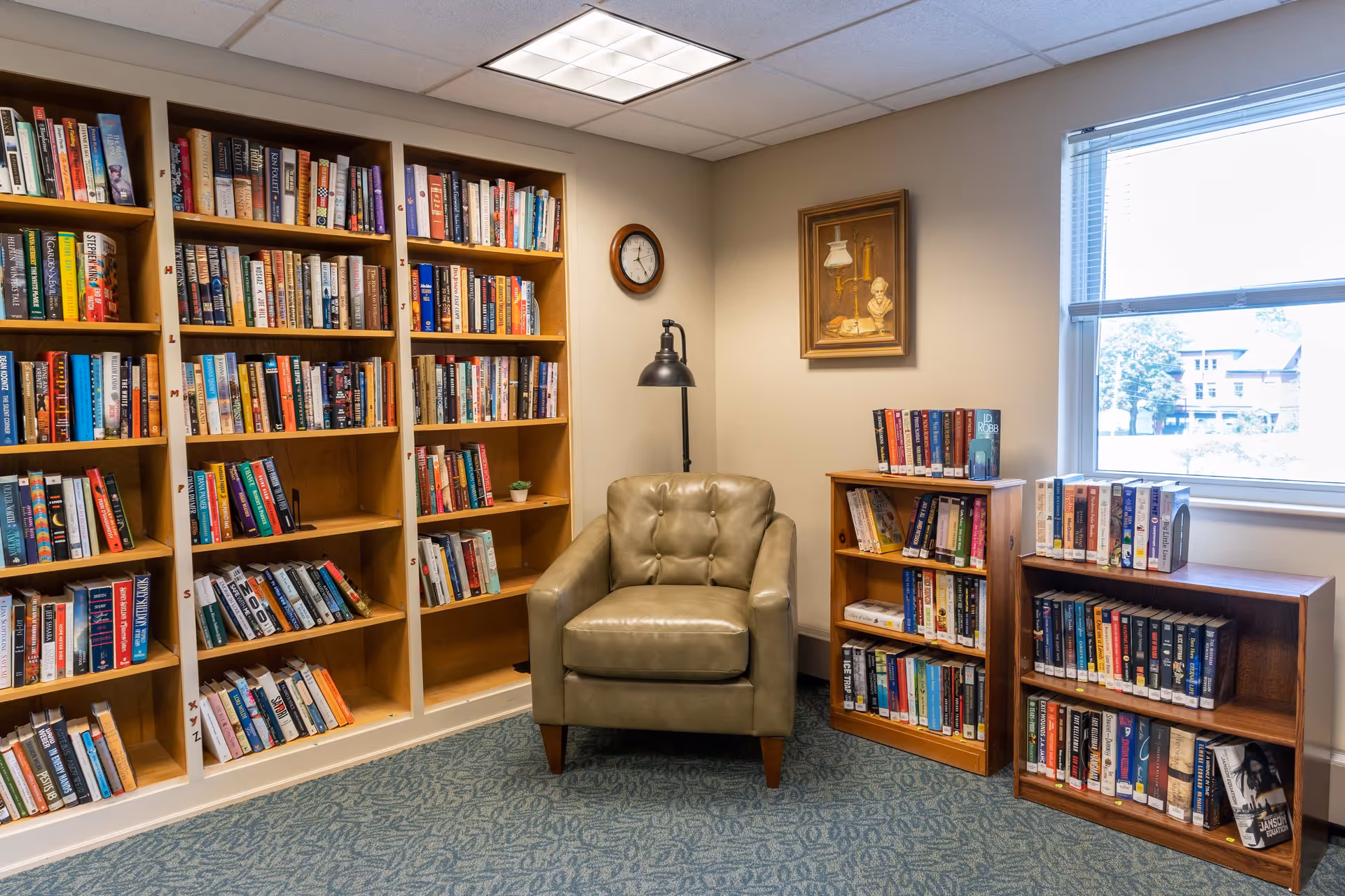 Cozy reading corner with a leather armchair flanked by bookshelves and a window.