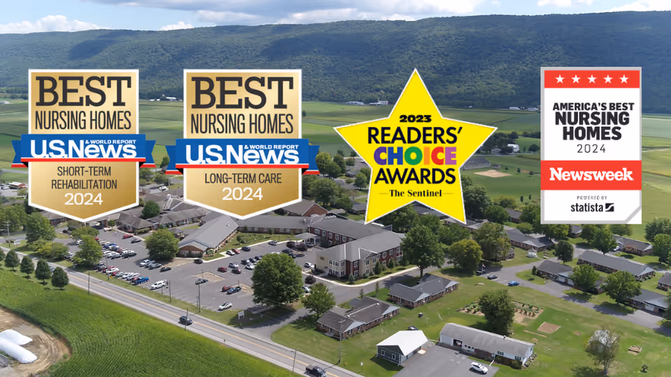 Aerial view of Valley View Retirement Community showing multiple buildings, parking lots, trees, and surrounding green fields with hills in the background. Overlaid on the image are four award badges for nursing homes and reader's choice awards from U.S. News, The Sentinel, and Newsweek.