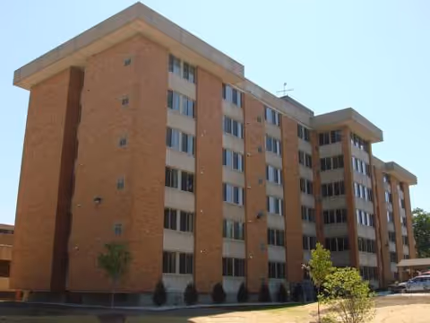 Exterior view of a brick, multi-story senior apartments building with several windows.