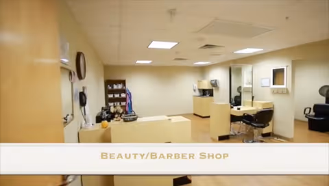 Interior view of a beauty/barber shop with styling chairs, counters, shelving, and mirrors under ceiling lights.