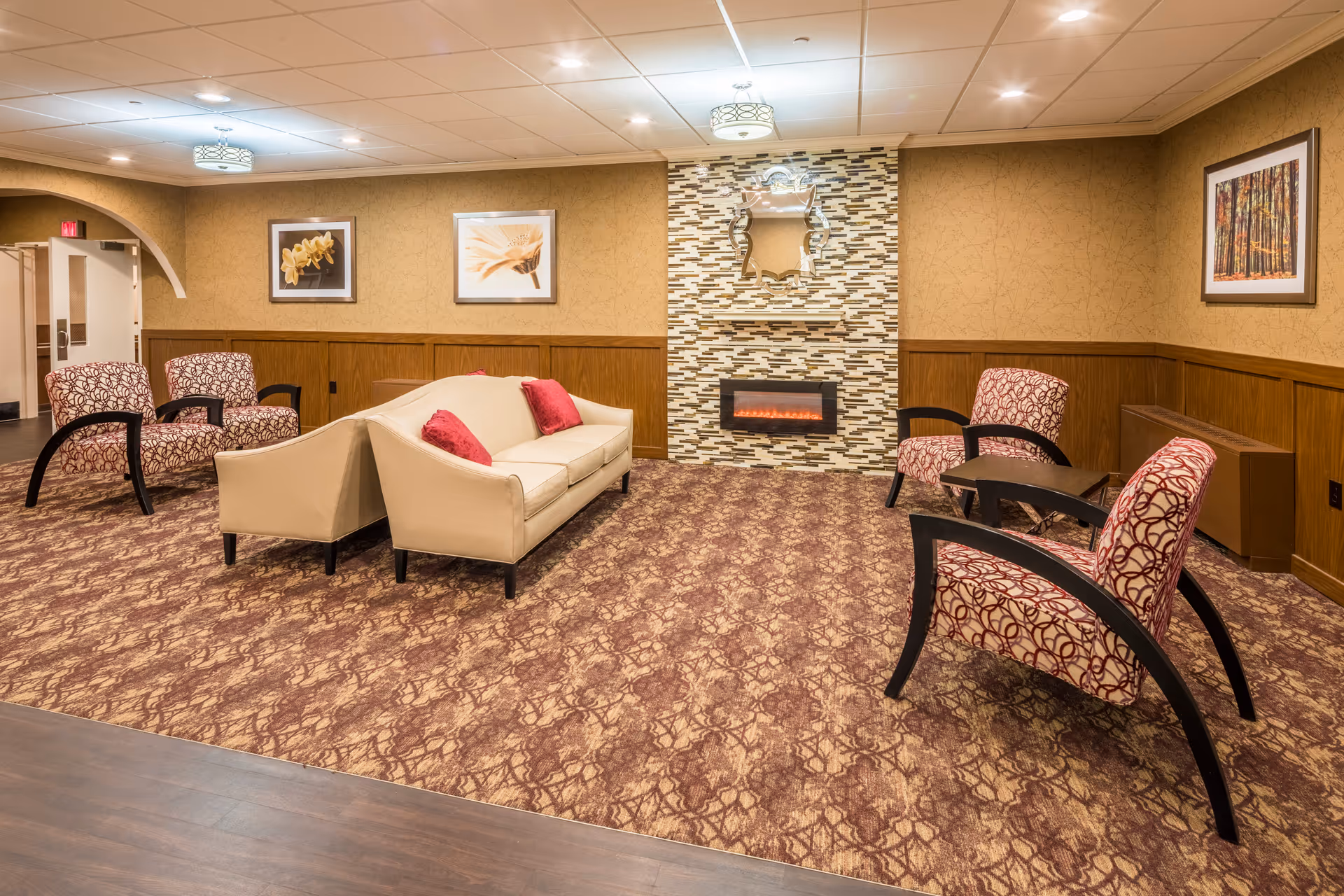 Community lounge with a sofa, patterned armchairs, a decorative fireplace and wall art.