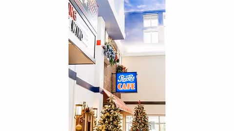 Indoor atrium with decorated Christmas trees, a hanging café sign and a skylight