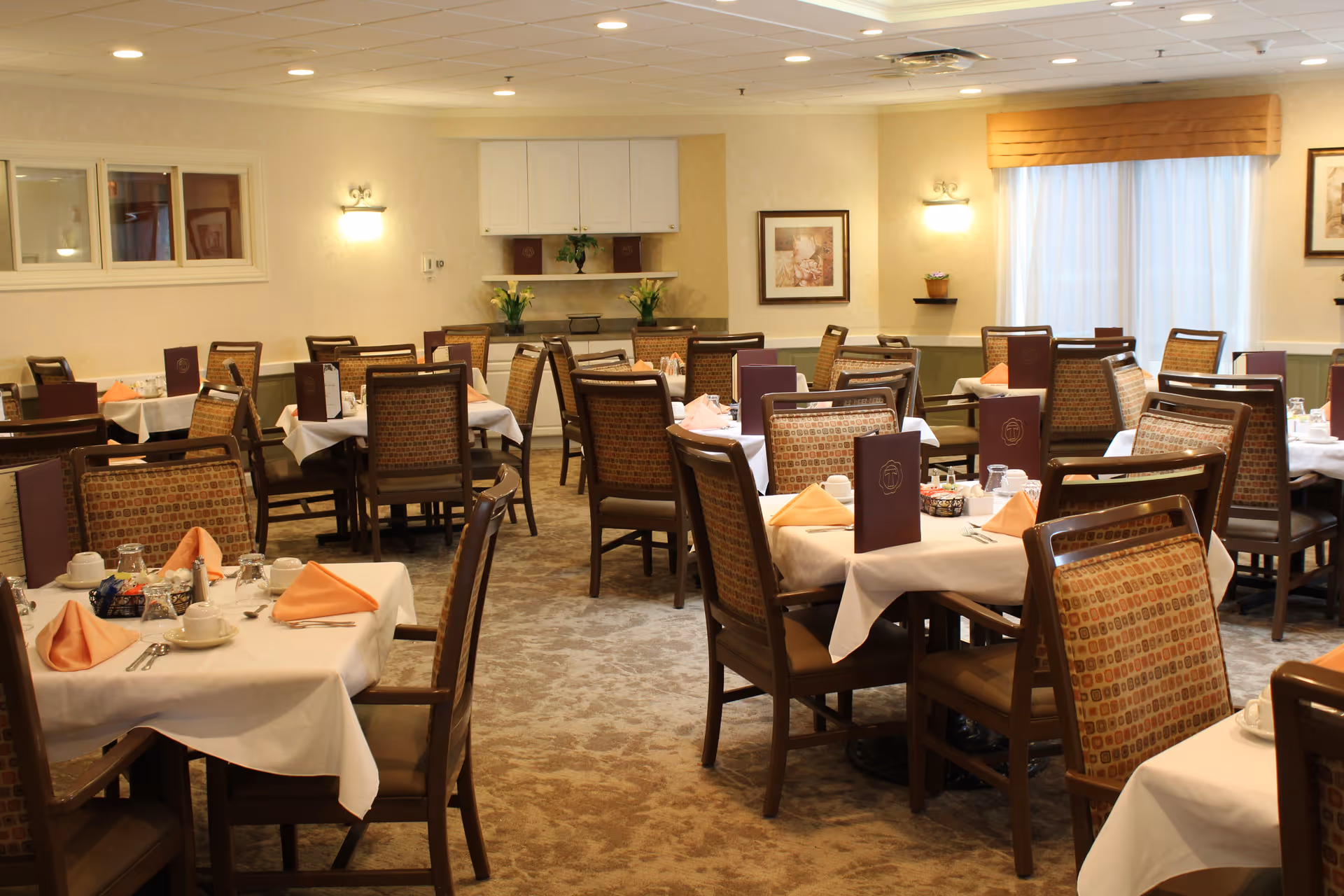 Spacious dining room with multiple set tables, chairs, folded napkins and menus.