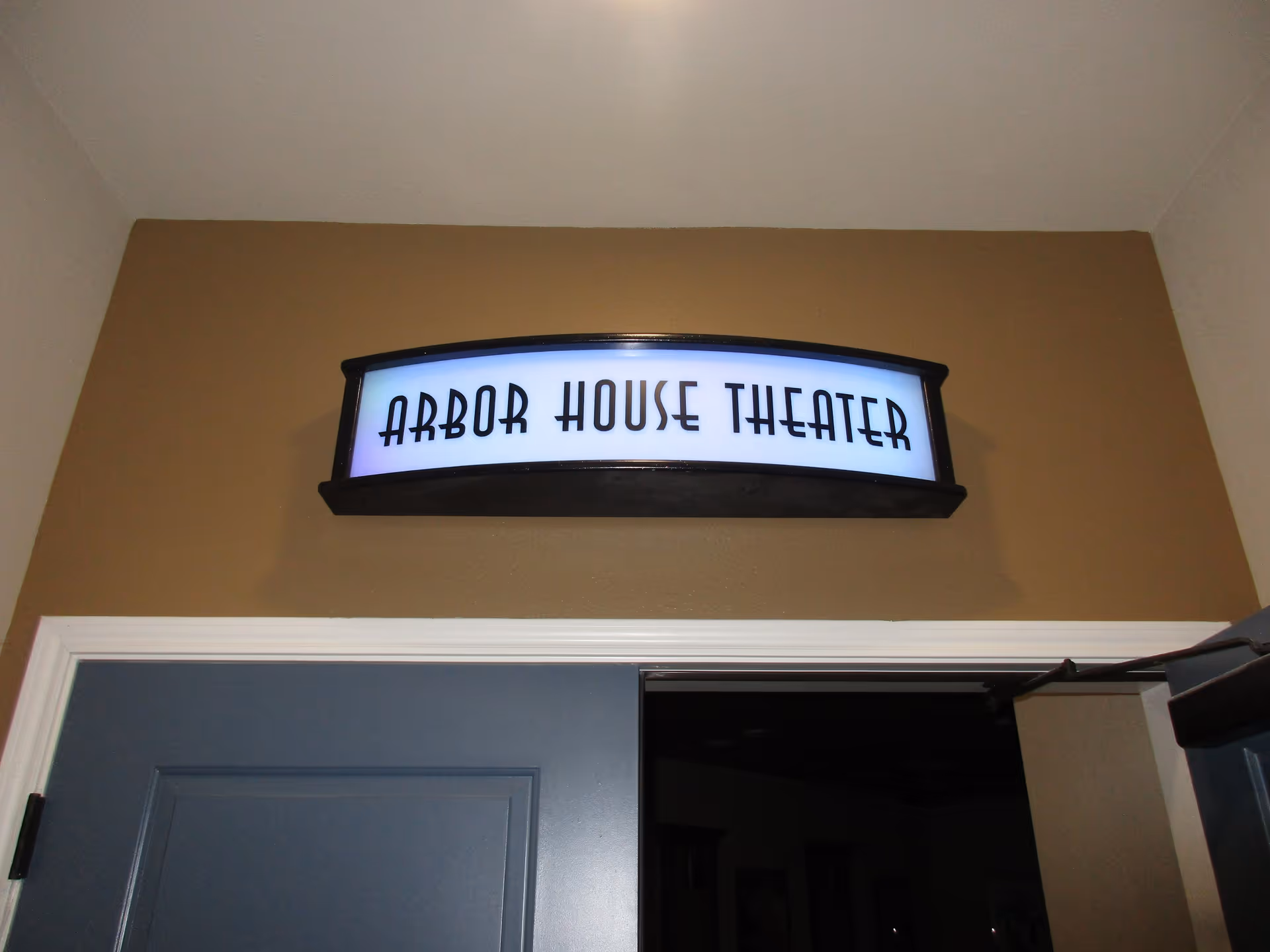 Illuminated 'Arbor House Theater' sign mounted above an interior doorway.
