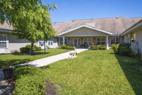 Exterior view of Worthington Place facility with a covered entrance and green lawn courtyard.