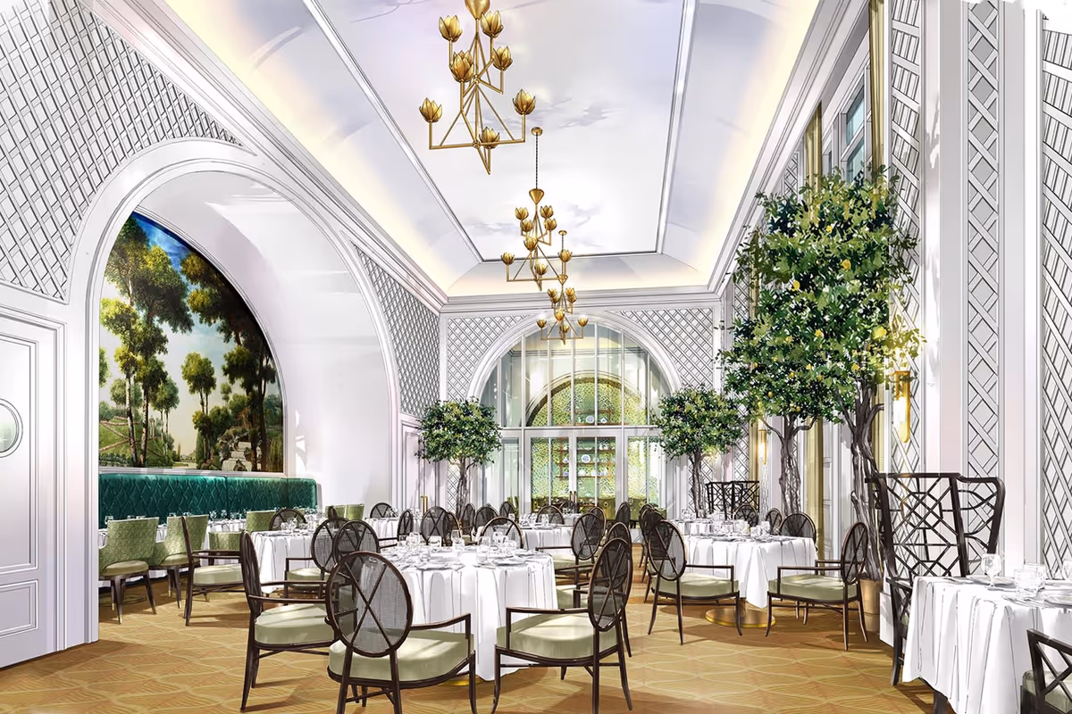 Elegant dining room with round tables covered in white tablecloths, set with glassware and silverware. The room features high ceilings with gold chandeliers, large arched windows, green cushioned chairs, and decorative indoor trees. A mural of a scenic landscape is visible through an archway on the left side.