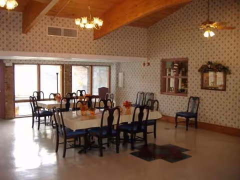 A dining room in a senior living facility with a long table and chairs.