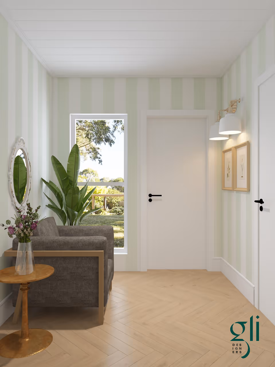 A small, cozy sitting area with a gray armchair next to a round wooden side table holding a vase with flowers. There is a large green plant behind the chair near a window showing an outdoor view with trees and greenery. The walls have light green and white vertical stripes, and two white doors with black handles are visible. Two framed botanical prints hang on the wall under two white wall lamps. The floor is light wood in a herringbone pattern.