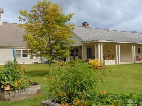 Whitney Hill Homestead exterior with lawn, garden beds, and a covered porch.