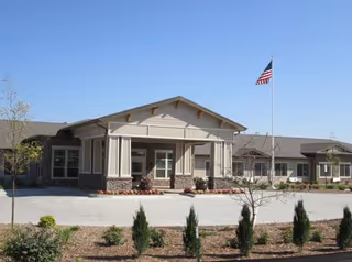 Front view of Cedar Creek of High Plains senior living facility with entrance canopy and flag.