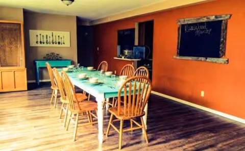A dining room with a long table, wooden chairs, and chalkboard walls.