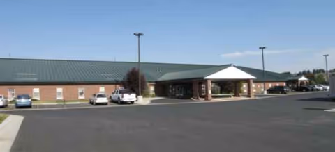 Exterior of a single-story senior living facility with a covered entrance and parking.