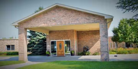 Brick-covered entrance to Heritage of Bel-Air senior living with glass doors.