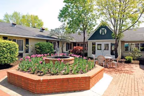 Exterior view of a senior living facility courtyard with a brick planter and seating.
