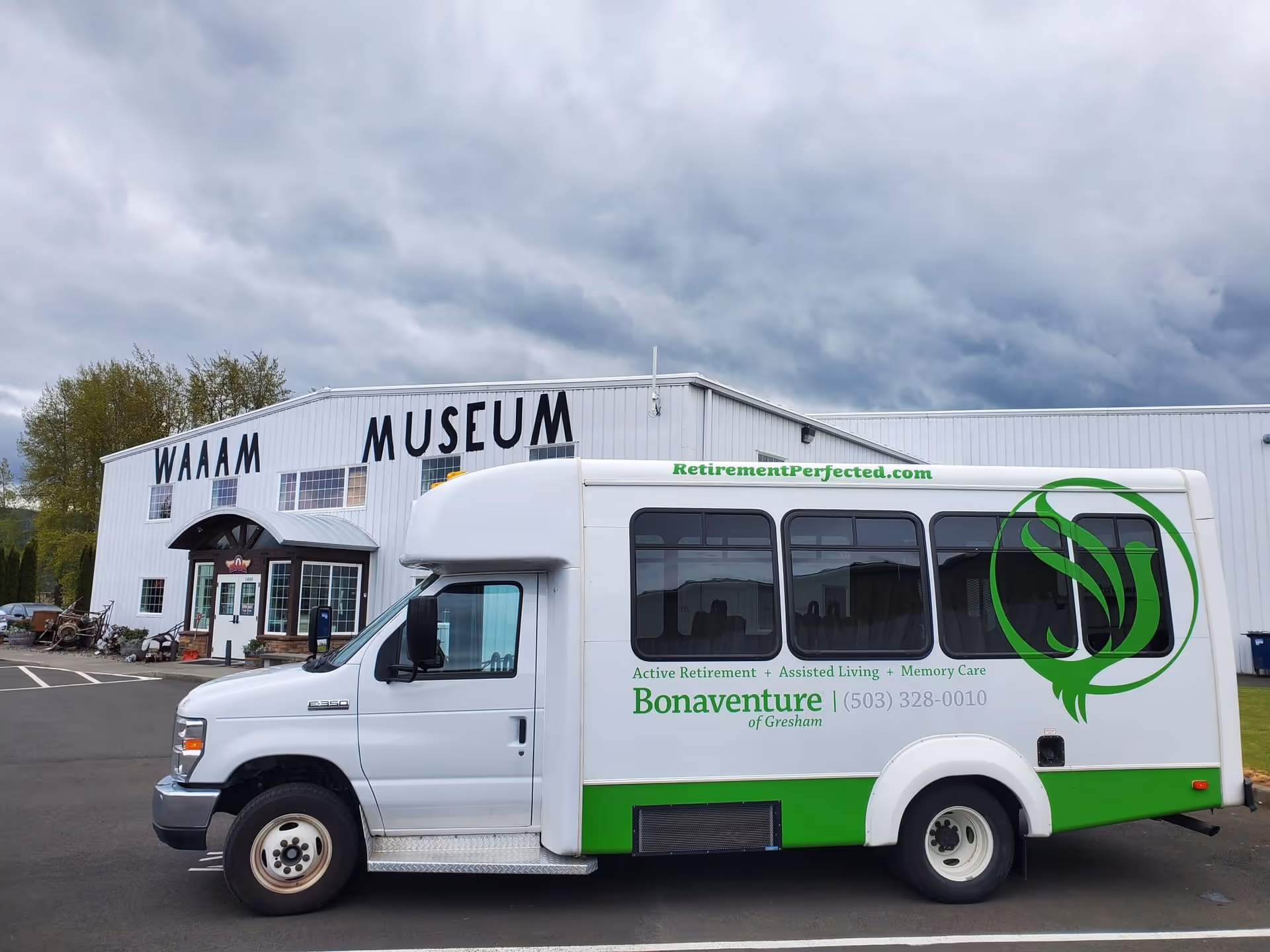 A white and green shuttle bus parked in front of a large white building with the sign 'WAAAM MUSEUM'. The bus has the logo and text for Bonaventure of Gresham, a senior living facility, including their phone number and website RetirementPerfected.com.