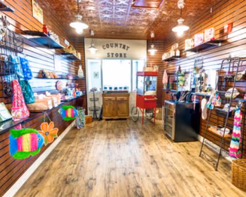 Interior view of a small 'Country Store' with wooden shelves and colorful gift items displayed along the walls.
