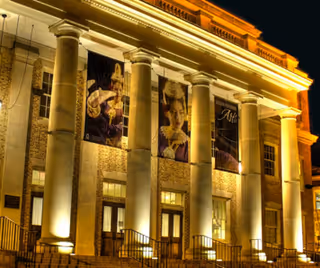 Illuminated neoclassical building façade with tall columns and banners at night.