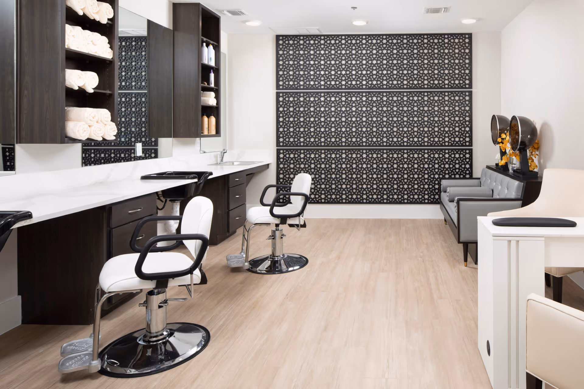 Bright modern salon area with styling chairs, mirrors, countertops, towel shelves and patterned decorative wall panels.