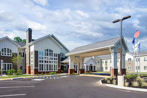 A senior living facility exterior with a covered entrance and parking.