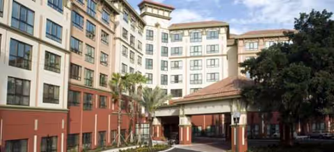 Exterior view of Freedom Pointe at the Villages with a covered entrance and palm trees.