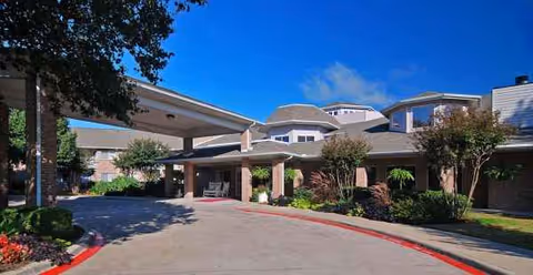 Exterior view of The El Dorado - Sky Active Living entrance with covered driveway and landscaping.