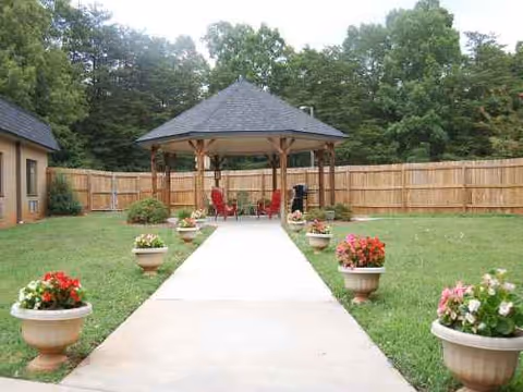 Senior living facility outdoor courtyard with gazebo, walkway, and potted flowers.