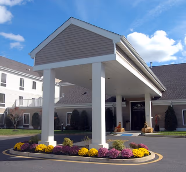 Exterior view of Mira Vie at Toms River entrance with a covered drop-off and flower bed.