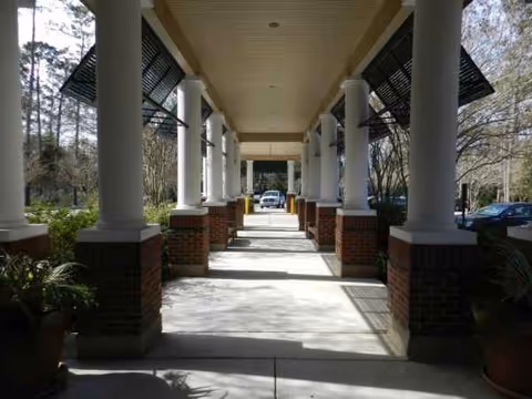 Covered outdoor walkway with columns leading to the facility entrance.