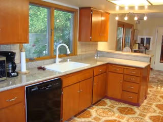 Wood cabinets, granite countertops, sink, and a windowed kitchen in a senior living facility.