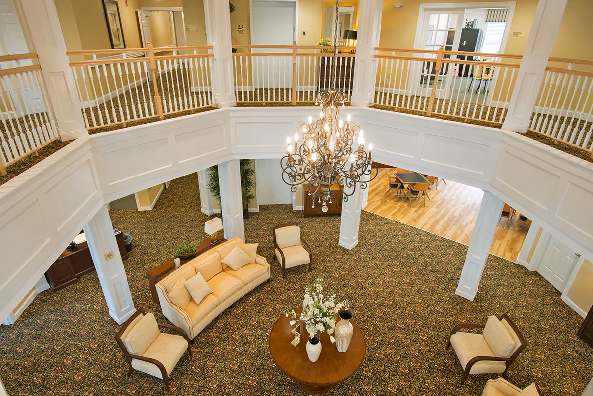 Two-story atrium lobby with a large chandelier and a seating area around a round table.
