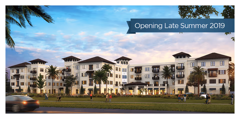 Exterior view of a large, modern senior living facility with multiple floors, balconies, palm trees, and people walking on the lawn in front. The sky is partly cloudy with a sunset glow.