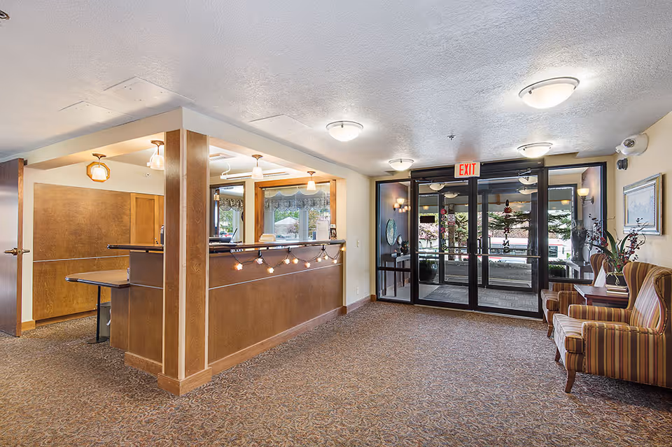 Lobby reception area with a wooden front desk, seating, and glass double entrance doors.